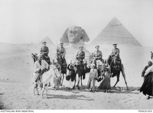 Outdoor group portrait of five Australian officers posing in front of the pyramids in Egypt. Cecil Beaumont Mills is on the horse first from right.