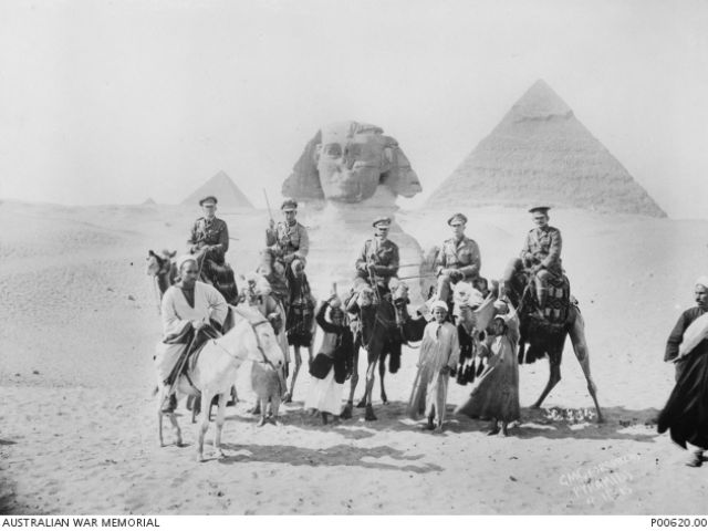 Outdoor group portrait of five Australian officers posing in front of the pyramids in Egypt. Cecil Beaumont Mills is on the horse first from right.